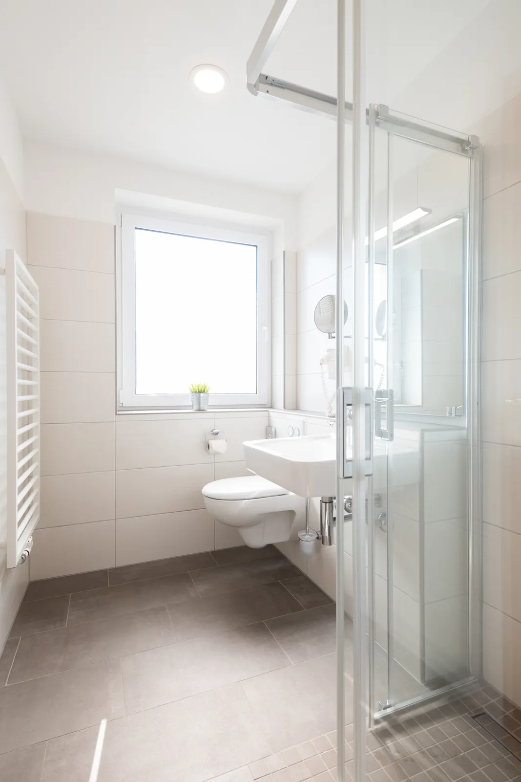 Modernes Badezimmer mit Glasdusche und Handtuchheizkörper in einem Cityapart Heiligenstadt Apartment